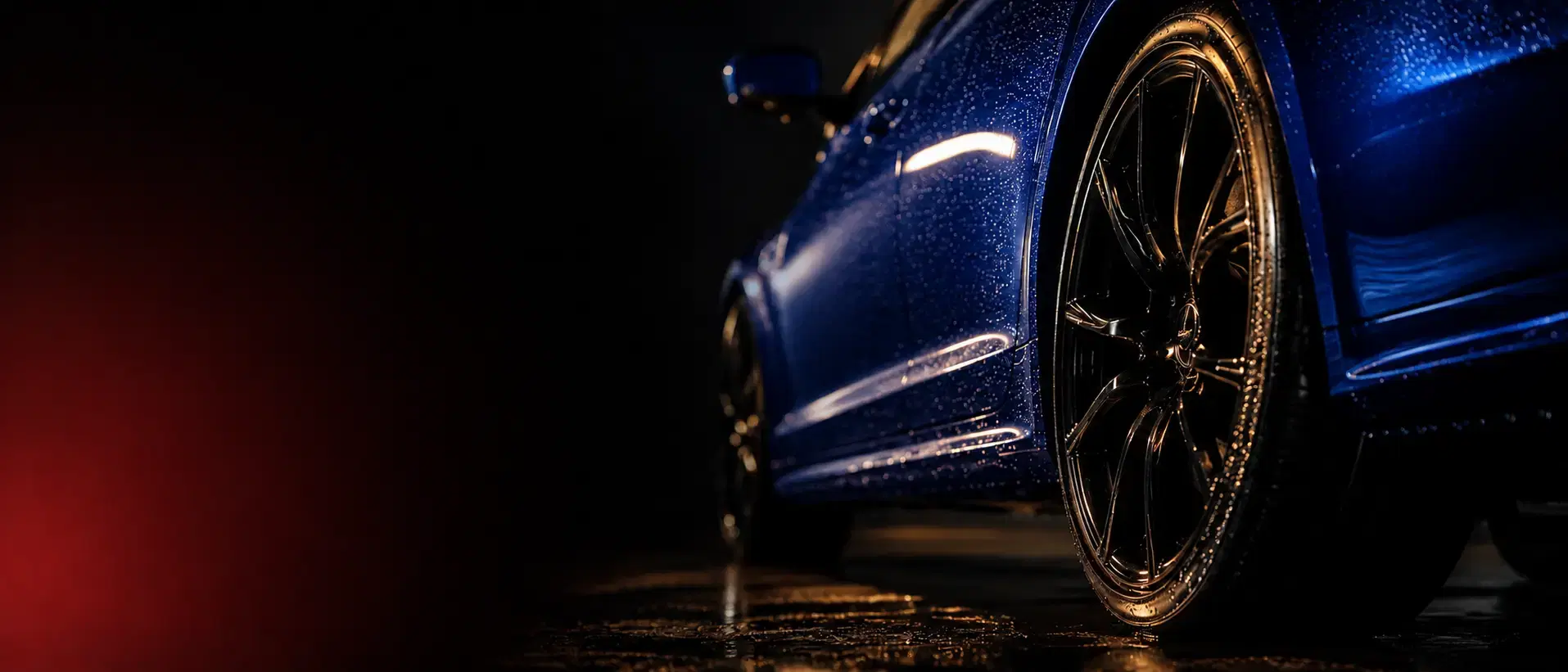 Glossy freshly detailed black car with beading water, front wheel in focus